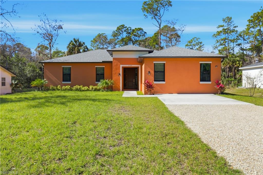View of front of property featuring a front yard, stucco siding, and roof with shingles