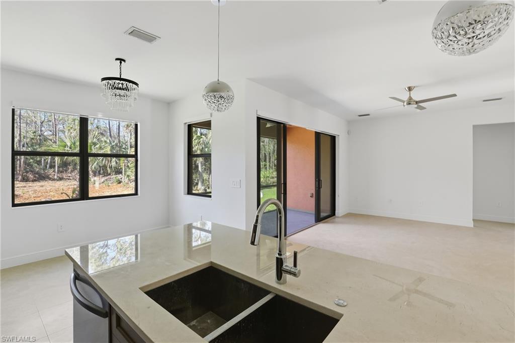 Kitchen featuring light stone countertops, open floor plan, healthy amount of natural light, and hanging light fixtures