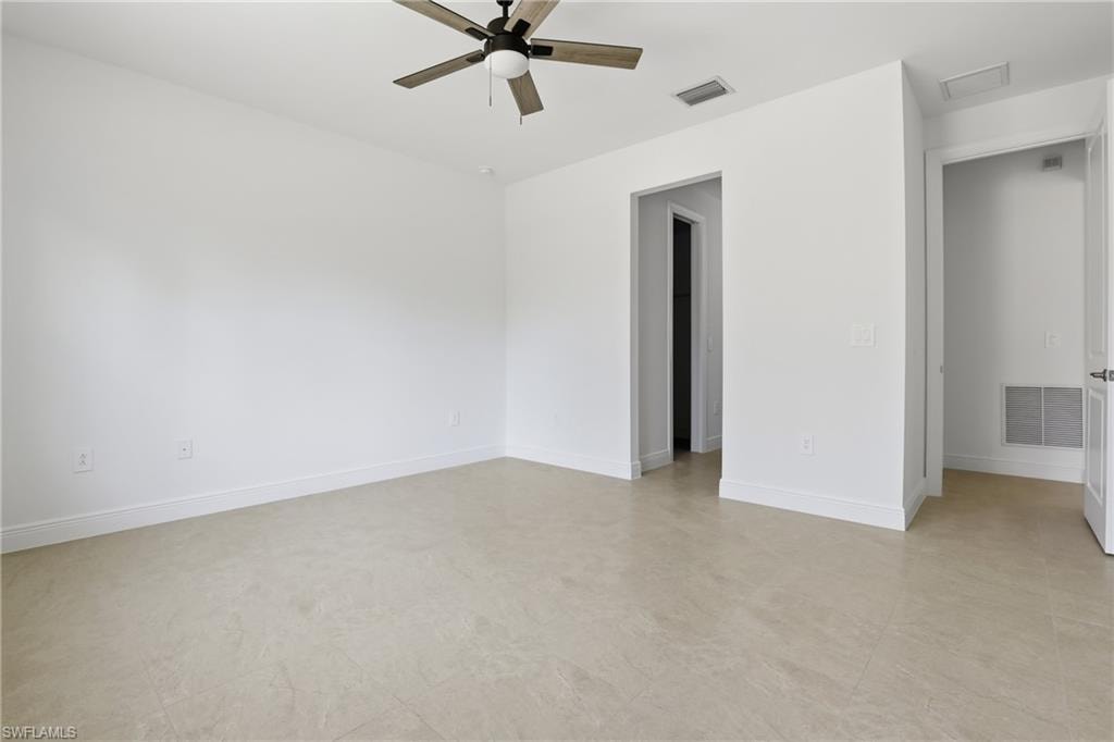 Empty room featuring ceiling fan and baseboards