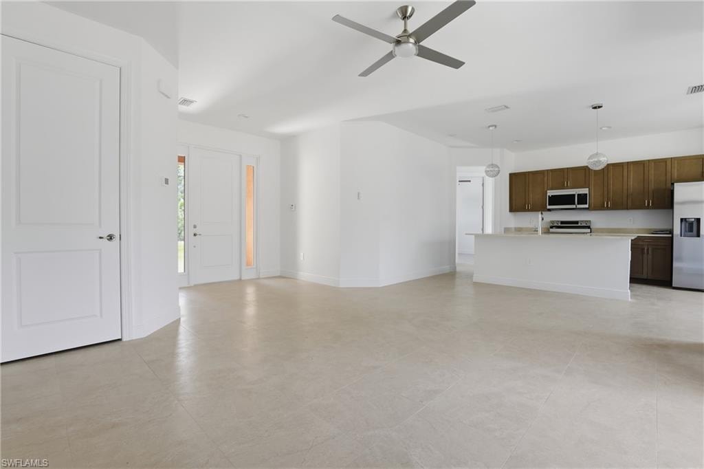 Unfurnished living room with a ceiling fan and baseboards
