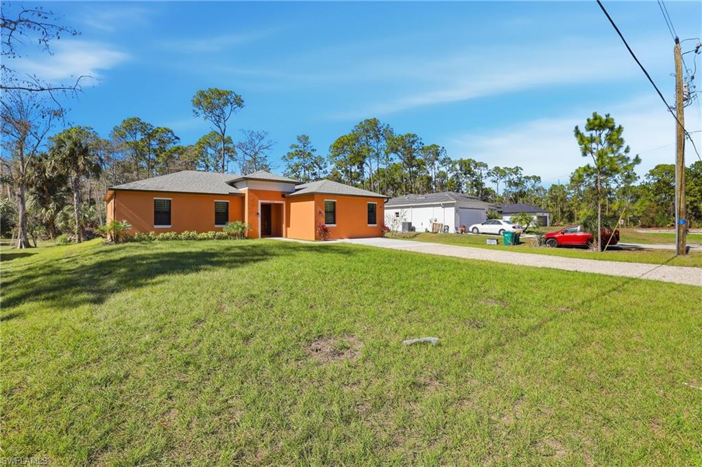 View of front of home with a front yard, stucco siding, and driveway