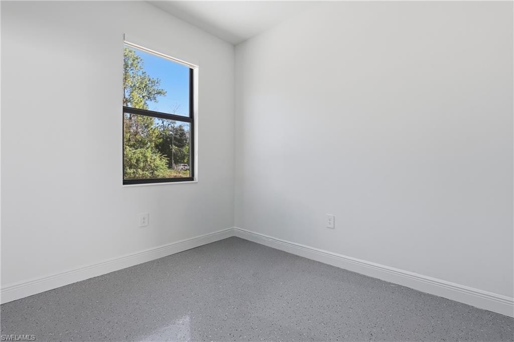 Unfurnished room featuring baseboards and speckle patterned floor
