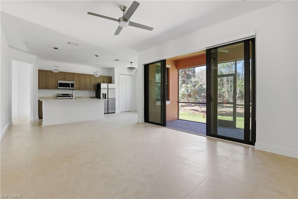 Unfurnished living room featuring baseboards and ceiling fan