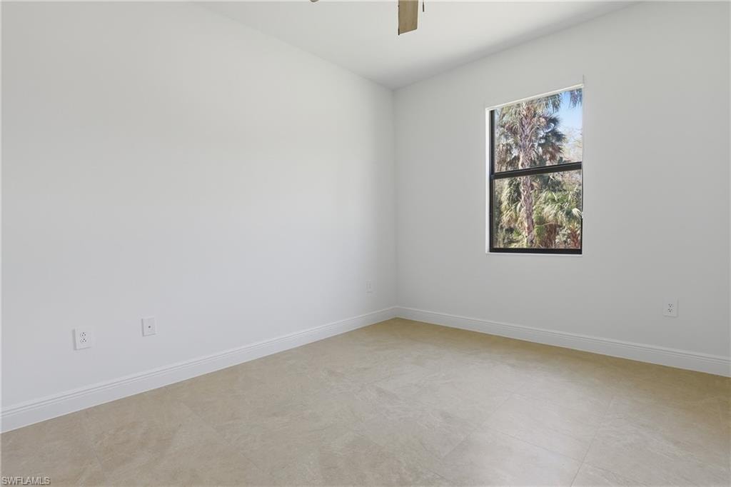 Spare room featuring a ceiling fan and baseboards