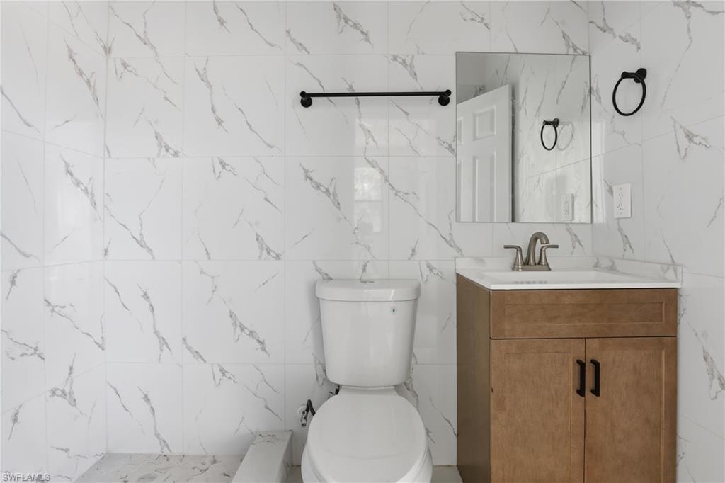 Full bath with tile walls, vanity, and a shower