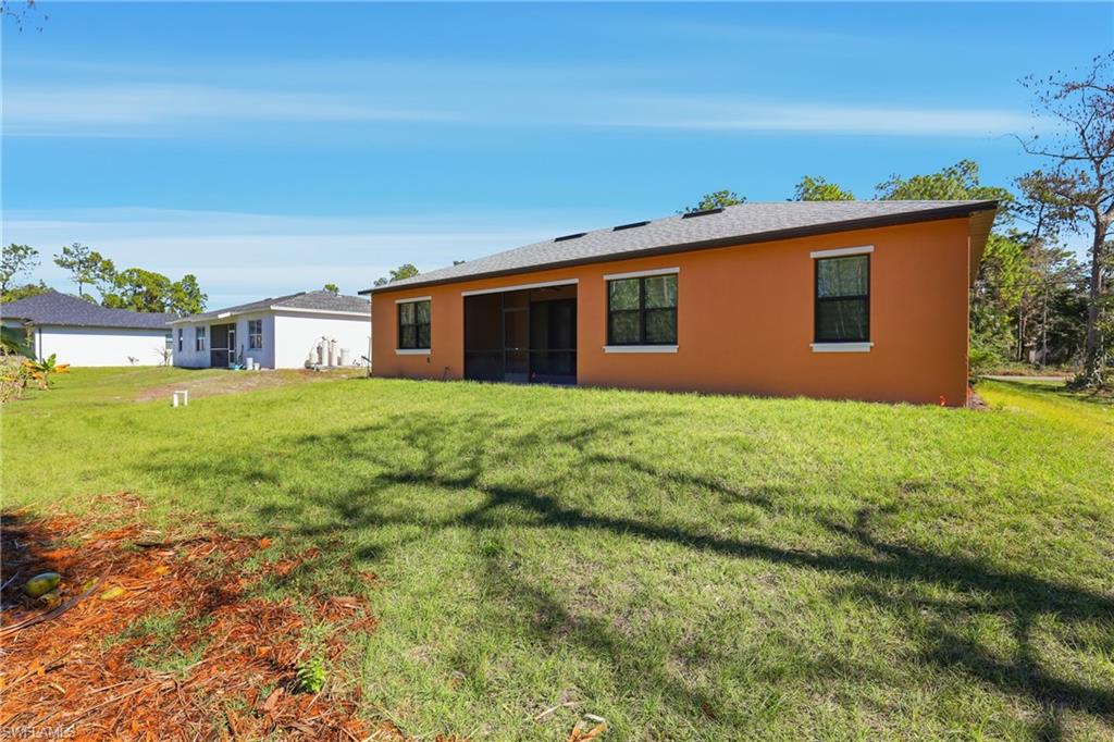 Back of house featuring a yard, stucco siding, and a sunroom