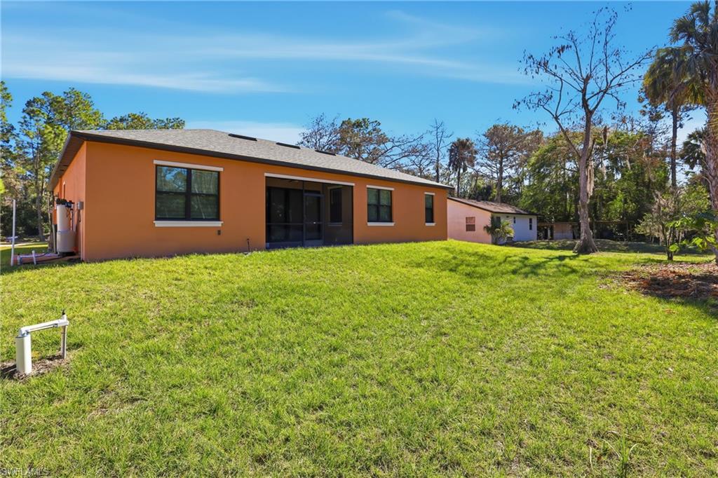 Back of property with a lawn, stucco siding, and a sunroom