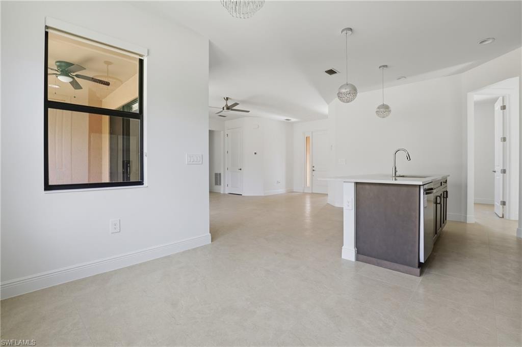 Kitchen featuring hanging light fixtures, a kitchen island with sink, open floor plan, dark brown cabinets, and stainless steel dishwasher