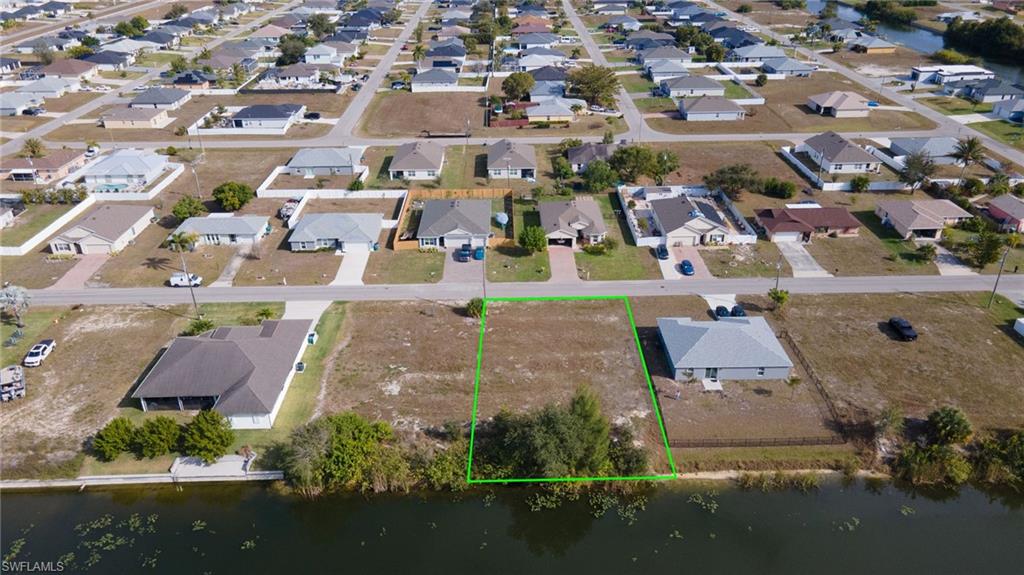 Aerial view of residential area featuring property boundaries highlighted and a large body of water