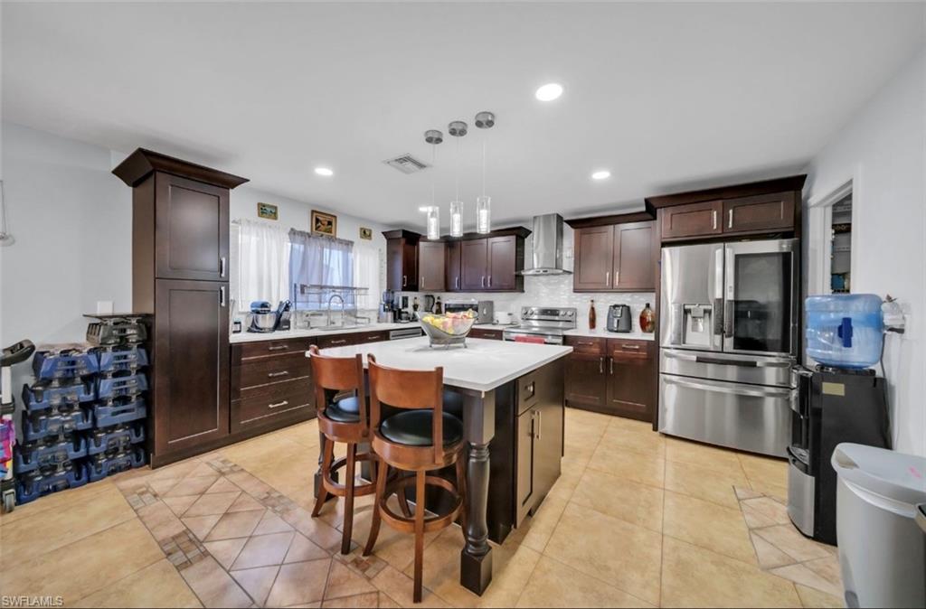 Kitchen featuring stainless steel appliances, dark brown cabinets, a kitchen breakfast bar, a center island, and recessed lighting