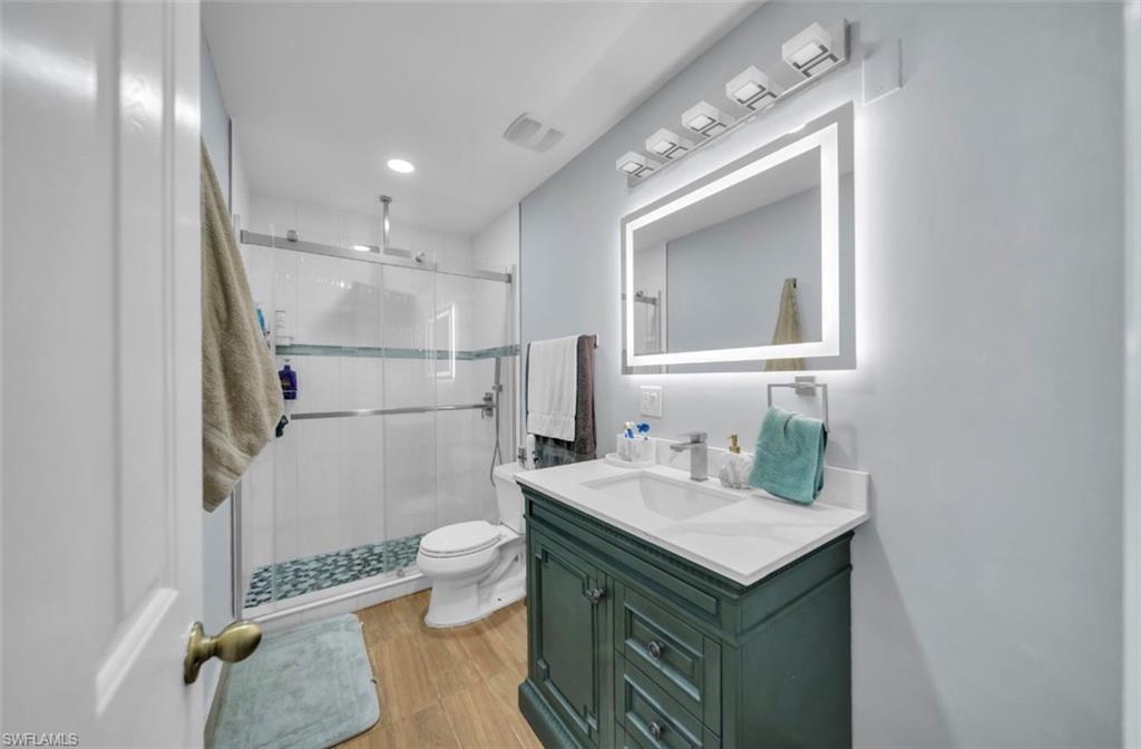Full bath featuring vanity, a shower stall, light wood-style floors, and recessed lighting
