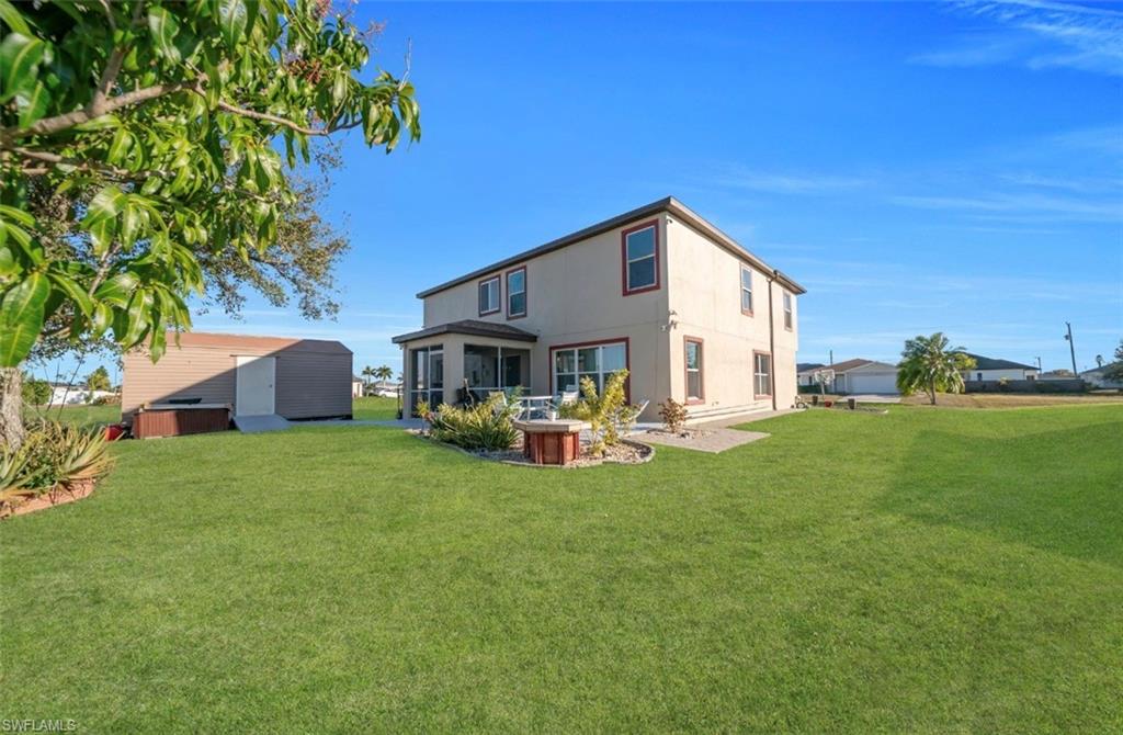 Rear view of house with a lawn, stucco siding, and a patio area