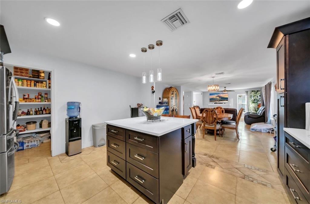 Kitchen with dark brown cabinetry, freestanding refrigerator, pendant lighting, a kitchen island, and recessed lighting