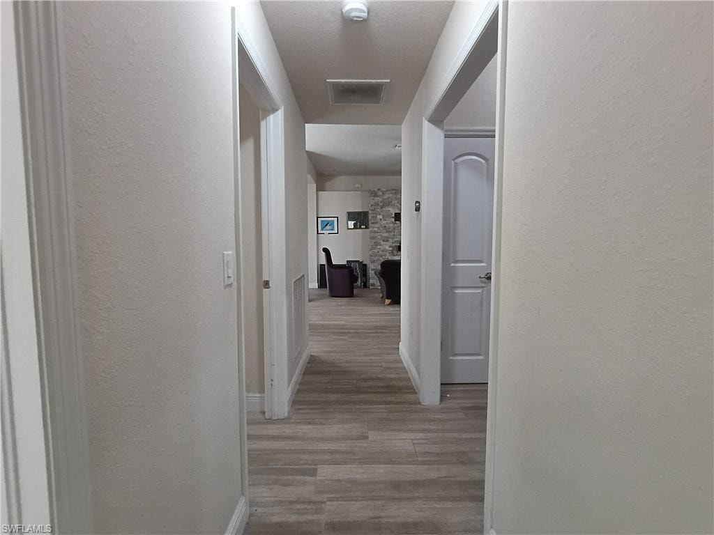 Corridor with a textured wall and light wood finished floors