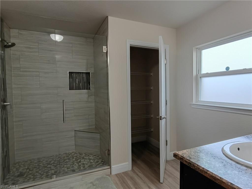 Bathroom featuring vanity, a stall shower, and light wood-type flooring