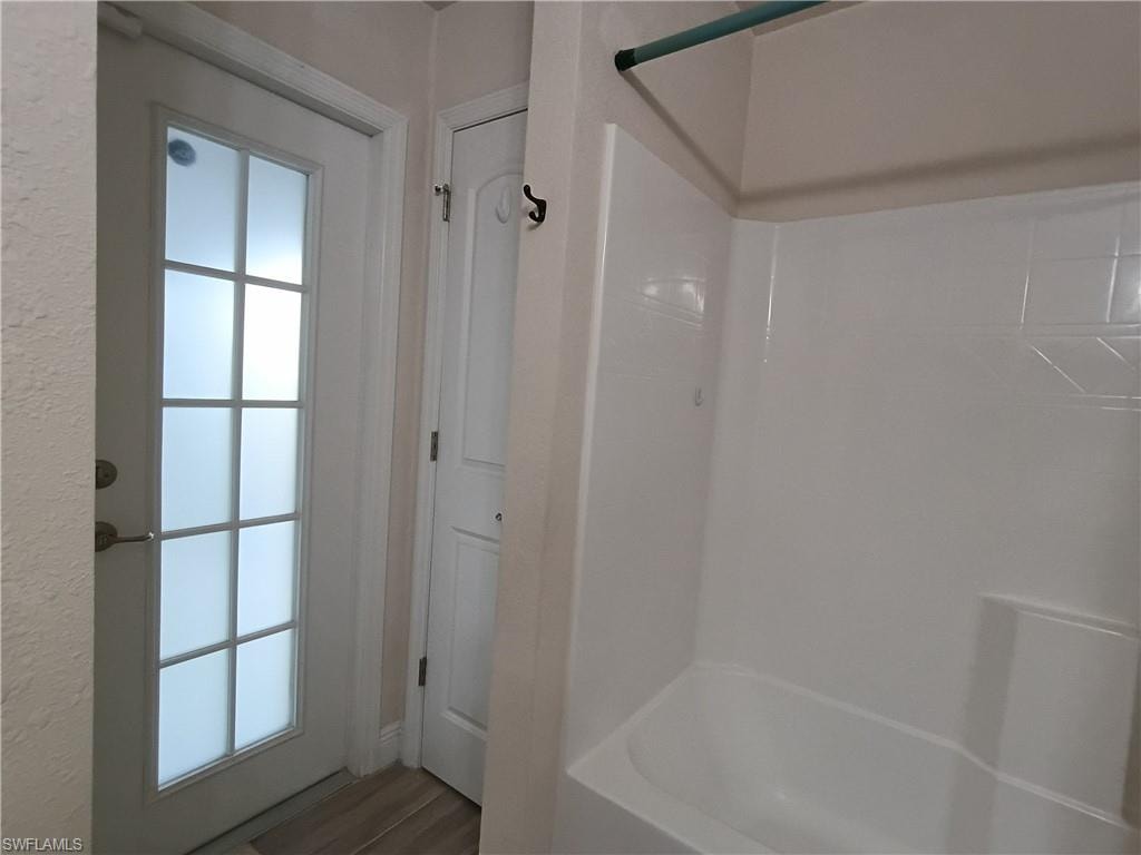 Full bath with shower / tub combination and wood finished floors