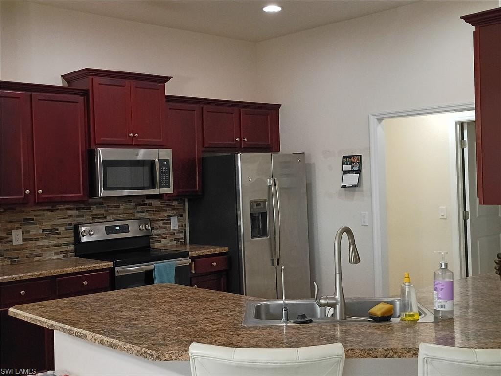 Kitchen with dark countertops, dark brown cabinets, stainless steel appliances, a peninsula, and recessed lighting