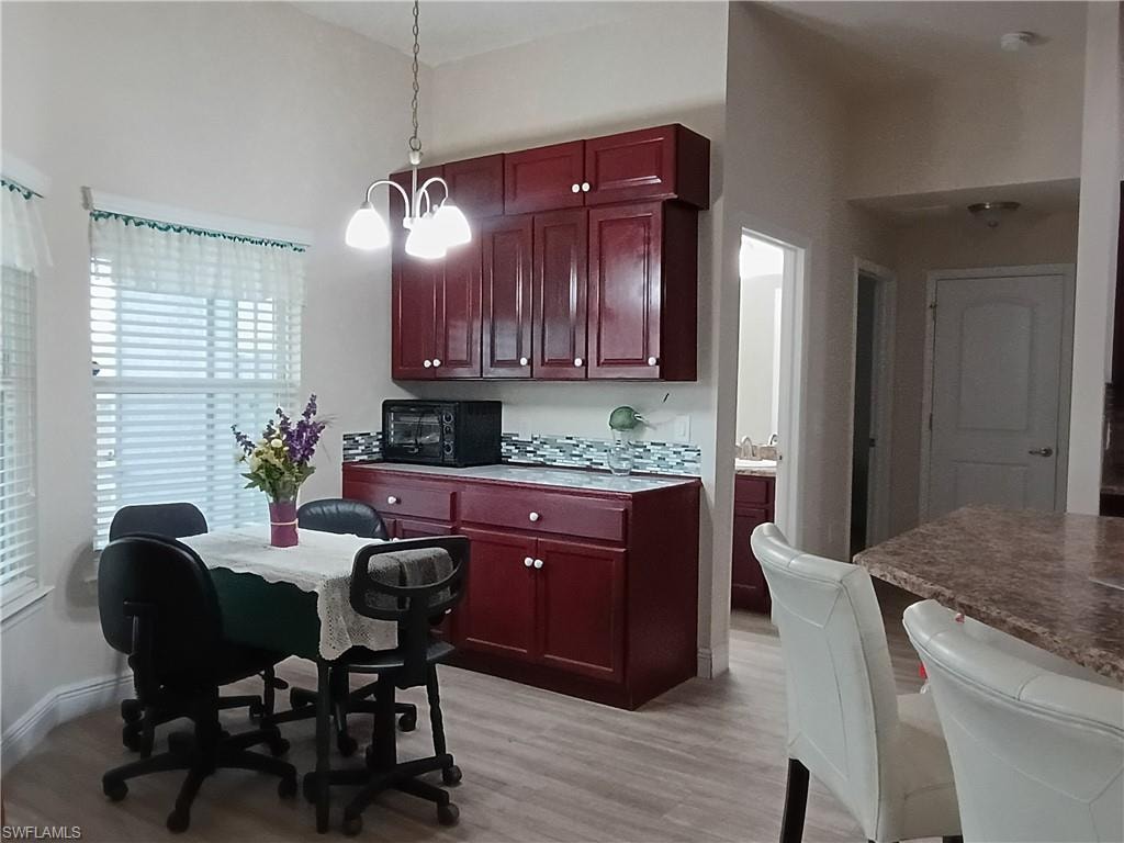 Kitchen featuring decorative light fixtures, dark brown cabinets, a chandelier, and black microwave
