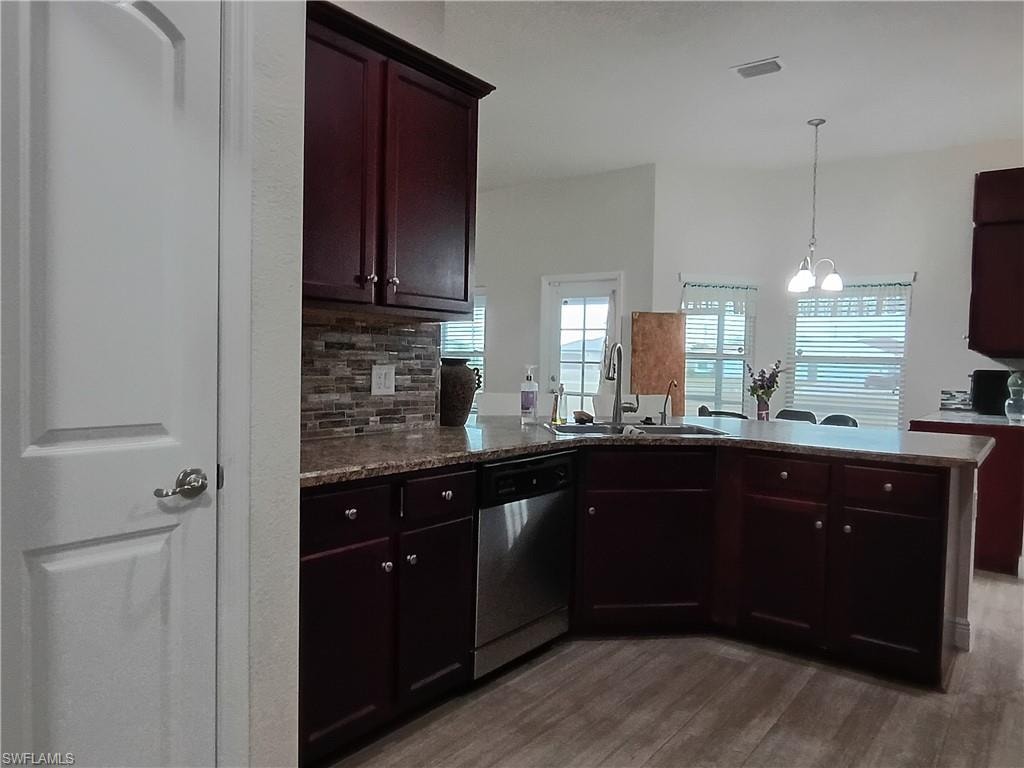 Kitchen featuring tasteful backsplash, a chandelier, dishwasher, a peninsula, and pendant lighting