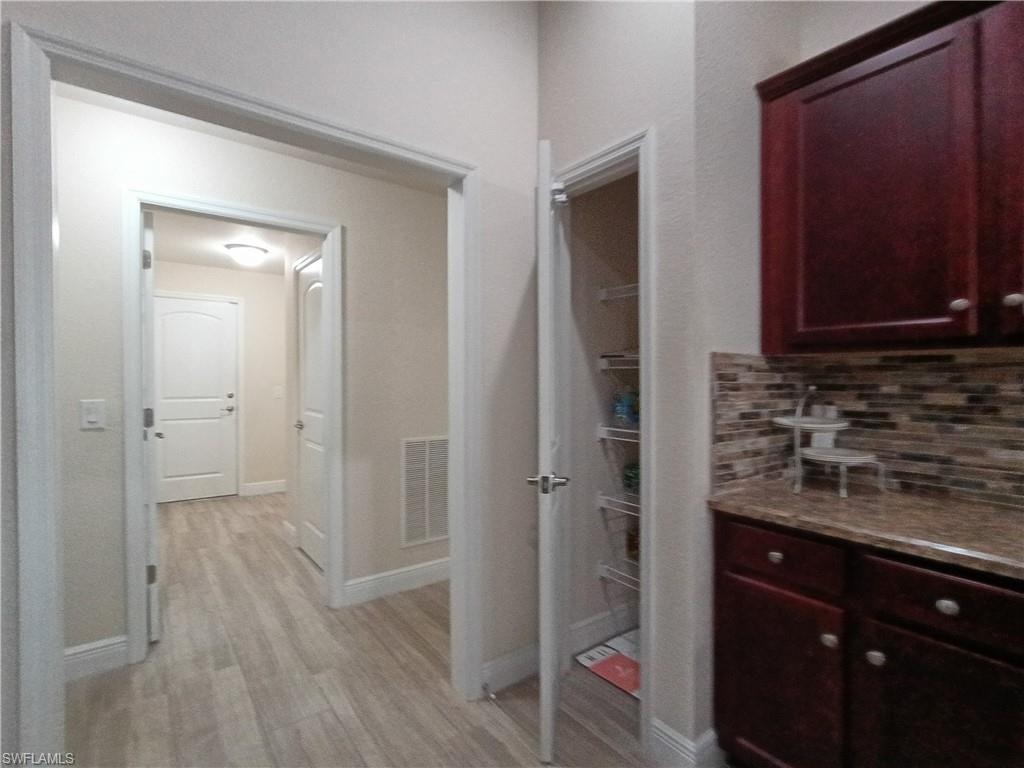 Hallway featuring light wood-type flooring and baseboards