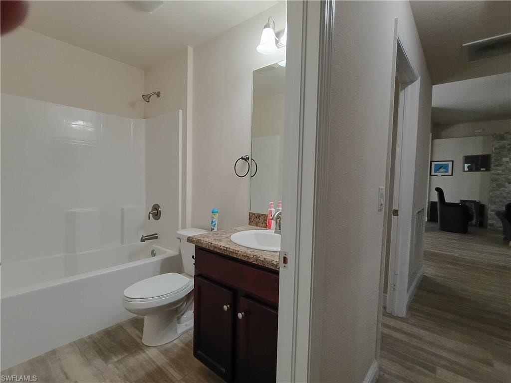 Bathroom featuring light wood-style flooring, vanity, and shower / bathtub combination