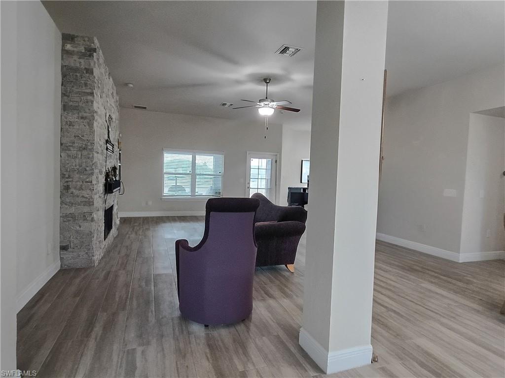 Living area featuring a fireplace, light wood finished floors, and ceiling fan