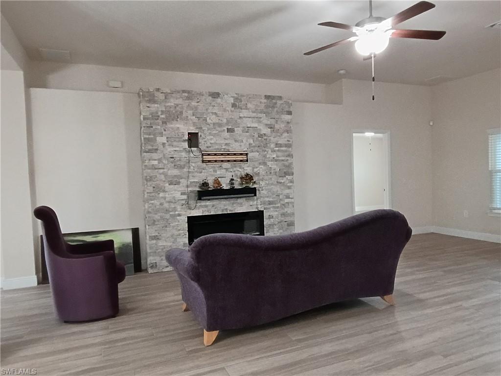 Living room featuring wood finished floors, a fireplace, and a ceiling fan