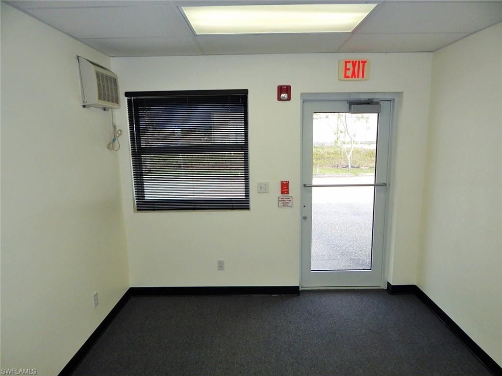 Spare room featuring a wall mounted AC and dark carpet