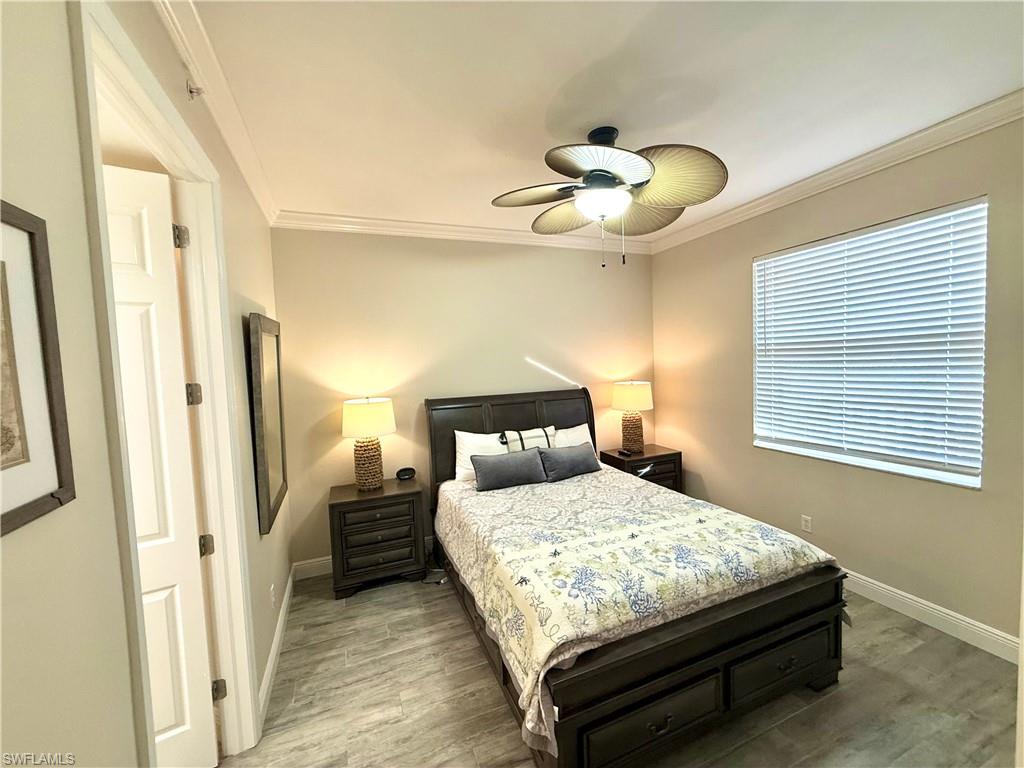 Bedroom with light wood finished floors, ornamental molding, and ceiling fan
