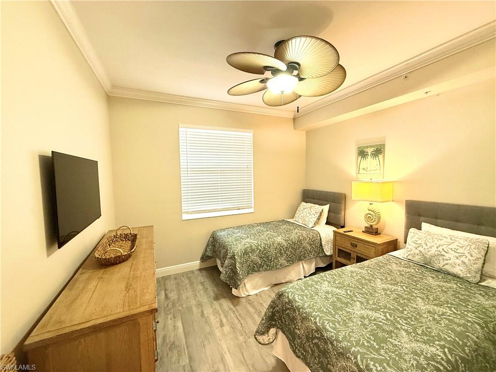 Bedroom with ornamental molding, ceiling fan, and light wood-style flooring