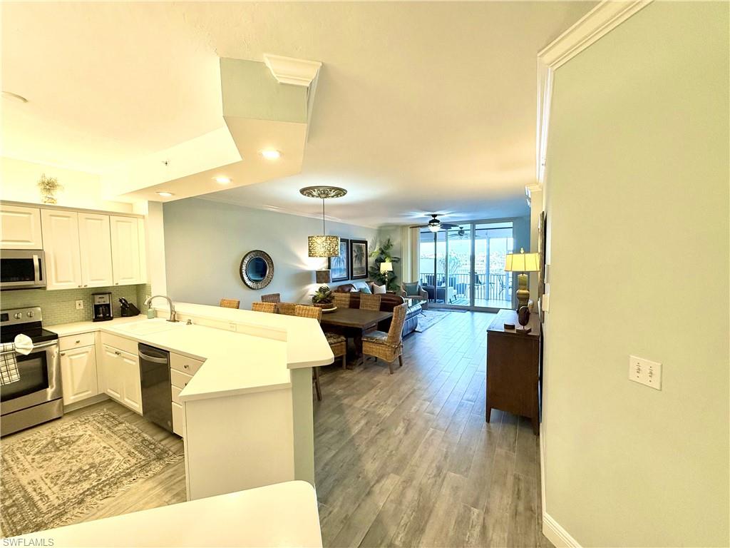 Kitchen featuring a peninsula, appliances with stainless steel finishes, light countertops, hanging light fixtures, and light wood-style floors