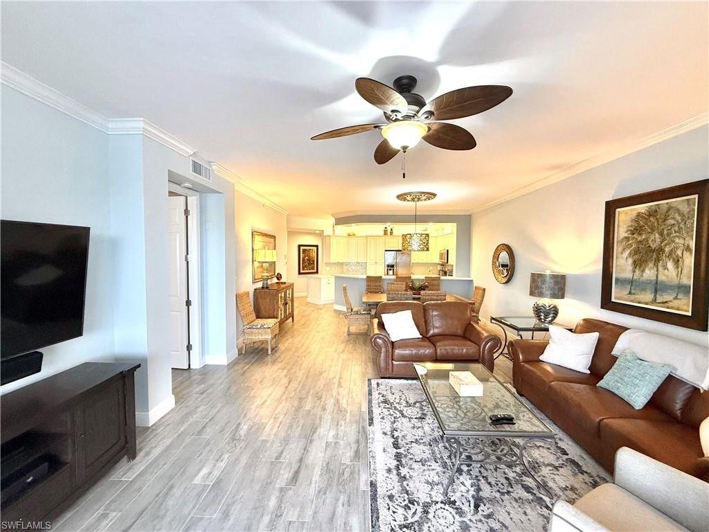 Living room with crown molding, a ceiling fan, and light wood-style flooring