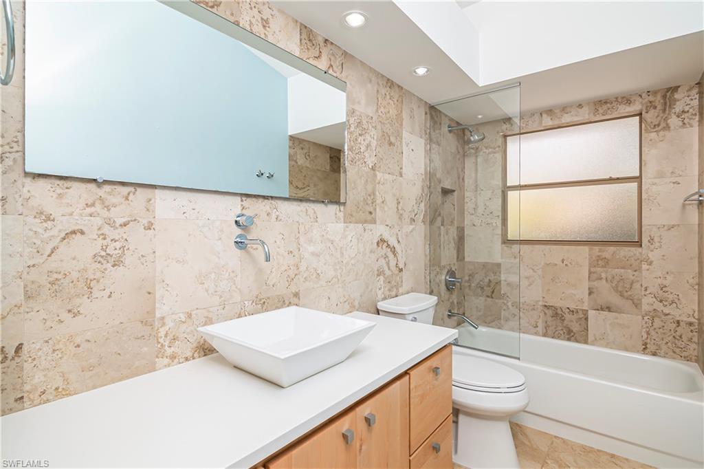 Full bath featuring shower / washtub combination, vanity, recessed lighting, and tile walls
