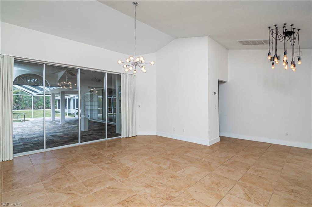 Unfurnished dining area with a chandelier, high vaulted ceiling, and a sunroom
