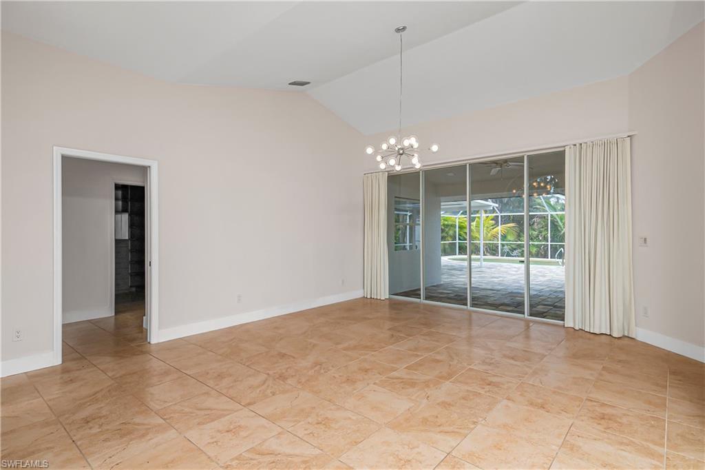 Empty room featuring a chandelier and high vaulted ceiling