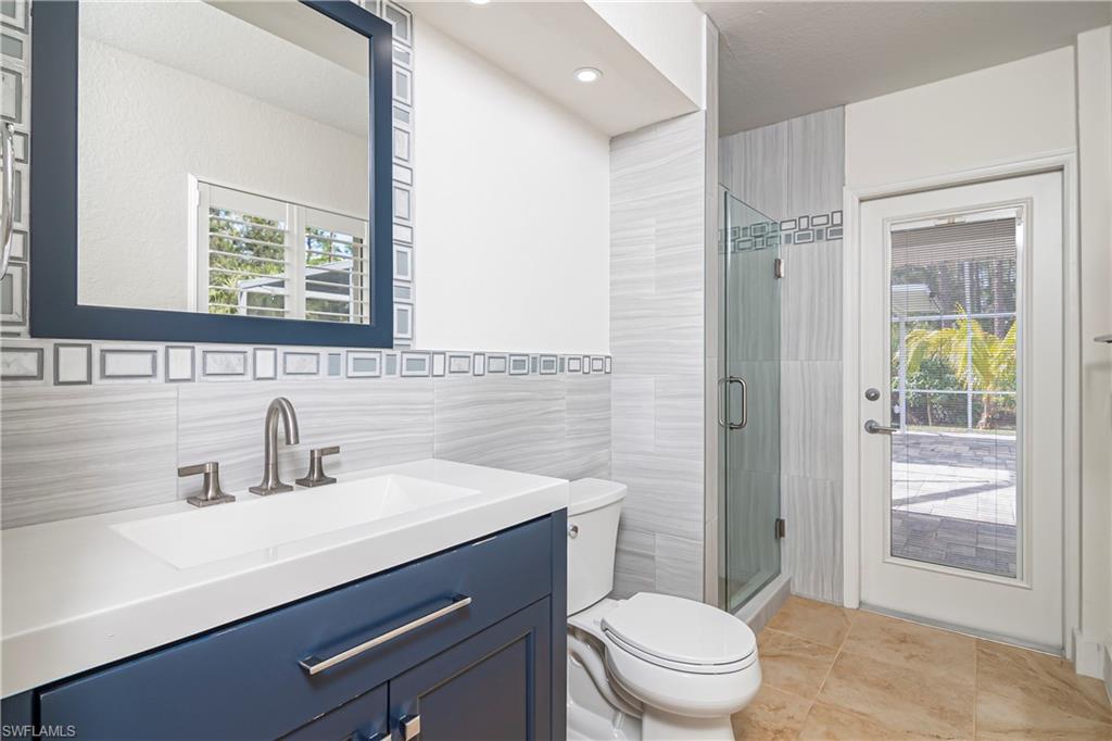 Bathroom featuring vanity, a stall shower, light tile patterned floors, and tile walls