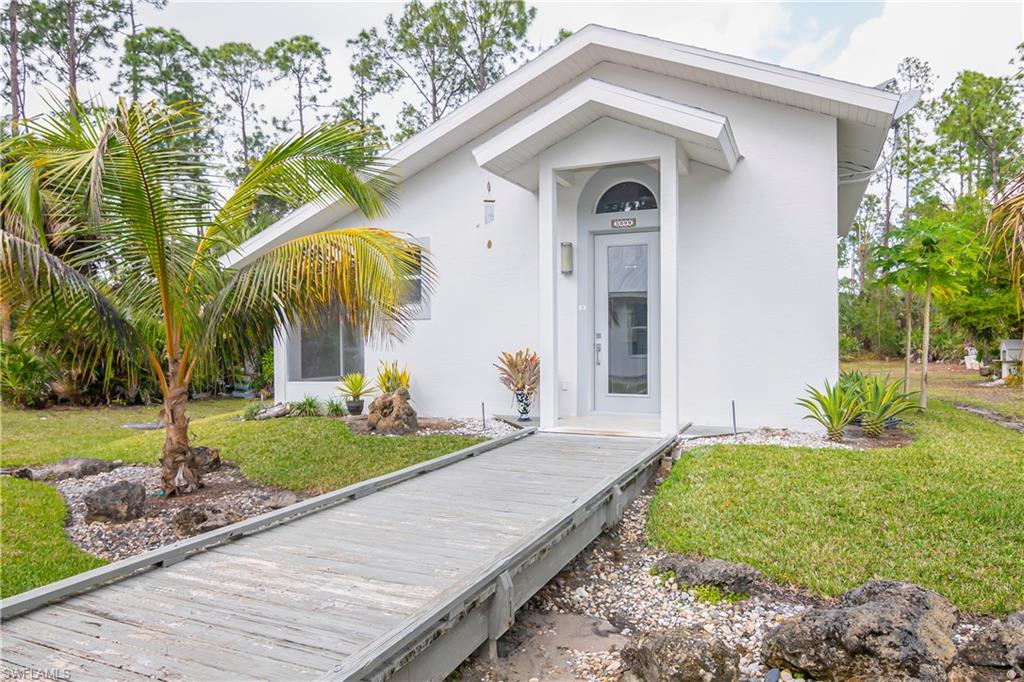 View of front of gueshouse featuring a metal roof, stucco siding, a garage, and driveway