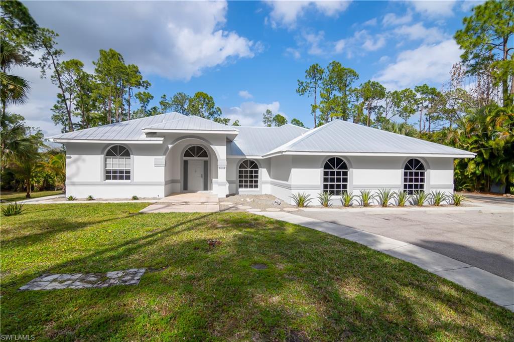 Ranch-style home with stucco siding, a front lawn, and a metal roof