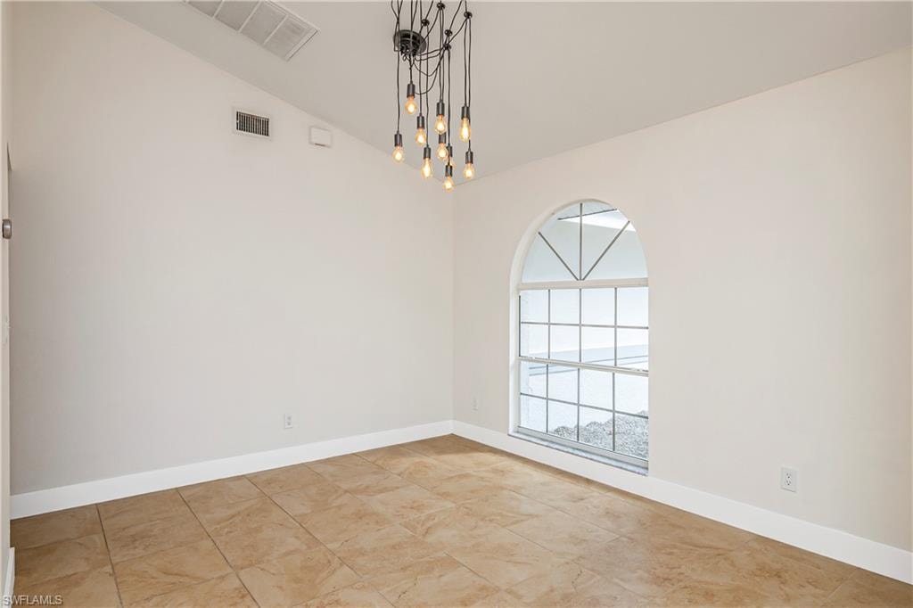 Empty room with vaulted ceiling and baseboards