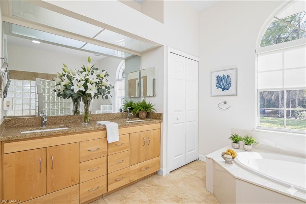 Bathroom featuring double vanity, a closet, and a bath