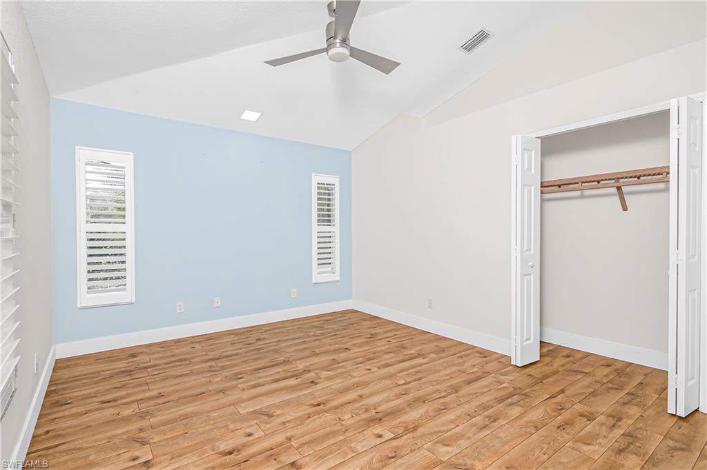 Unfurnished bedroom featuring lofted ceiling, light wood-style flooring, a ceiling fan, and a closet