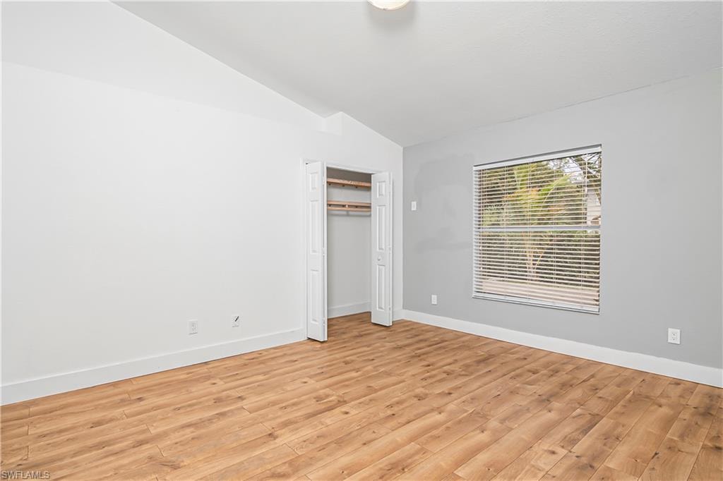 Unfurnished bedroom featuring lofted ceiling, light wood-type flooring, and a closet