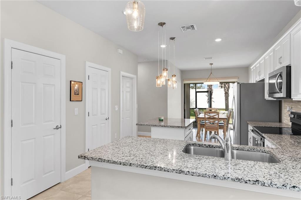 Kitchen featuring white cabinetry, hanging light fixtures, stainless steel appliances, light stone counters, and recessed lighting