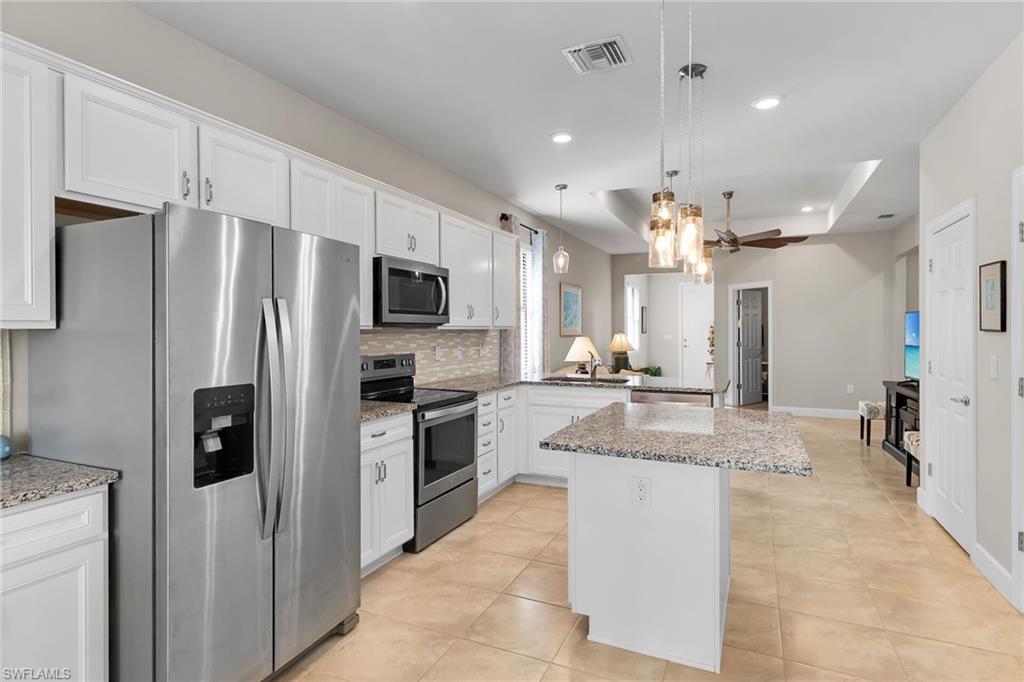 Kitchen featuring stainless steel appliances, white cabinets, a peninsula, light stone countertops, and recessed lighting