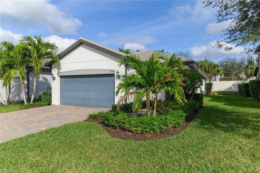 View of front facade with stucco siding, decorative driveway, and an attached garage
