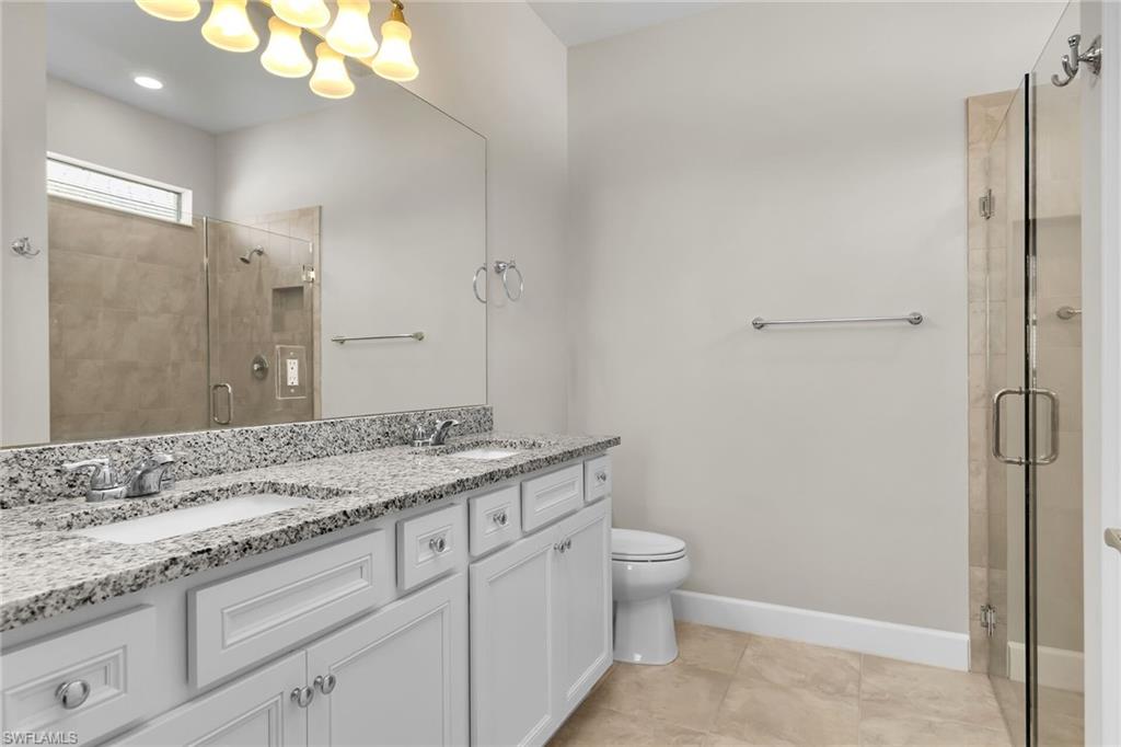 Full bath with double vanity, a shower stall, and light tile patterned floors