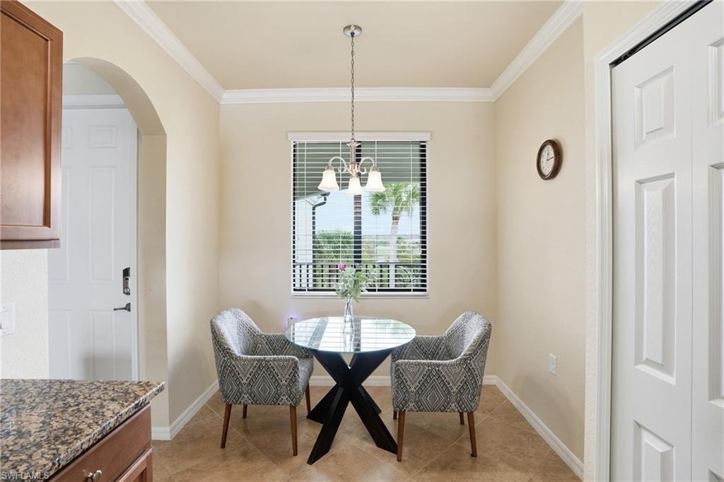 Dining area featuring arched walkways, ornamental molding, a chandelier, and light tile patterned floors