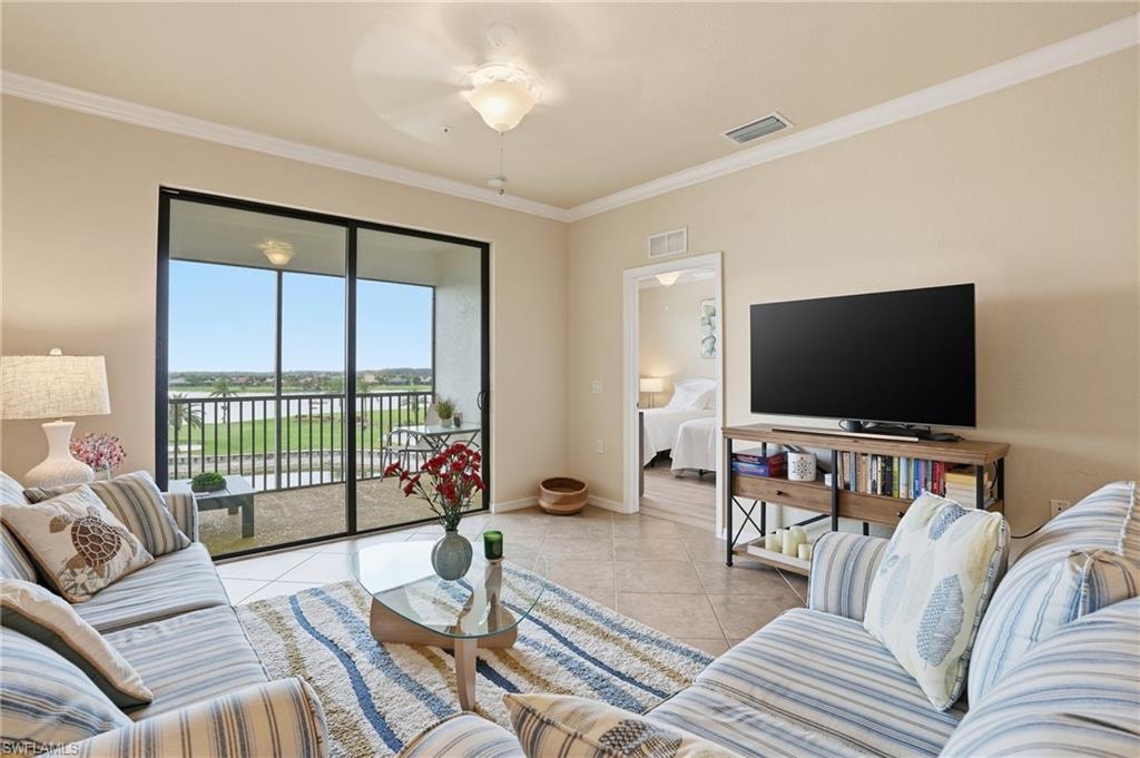 Living area featuring light tile patterned flooring, crown molding, and a ceiling fan