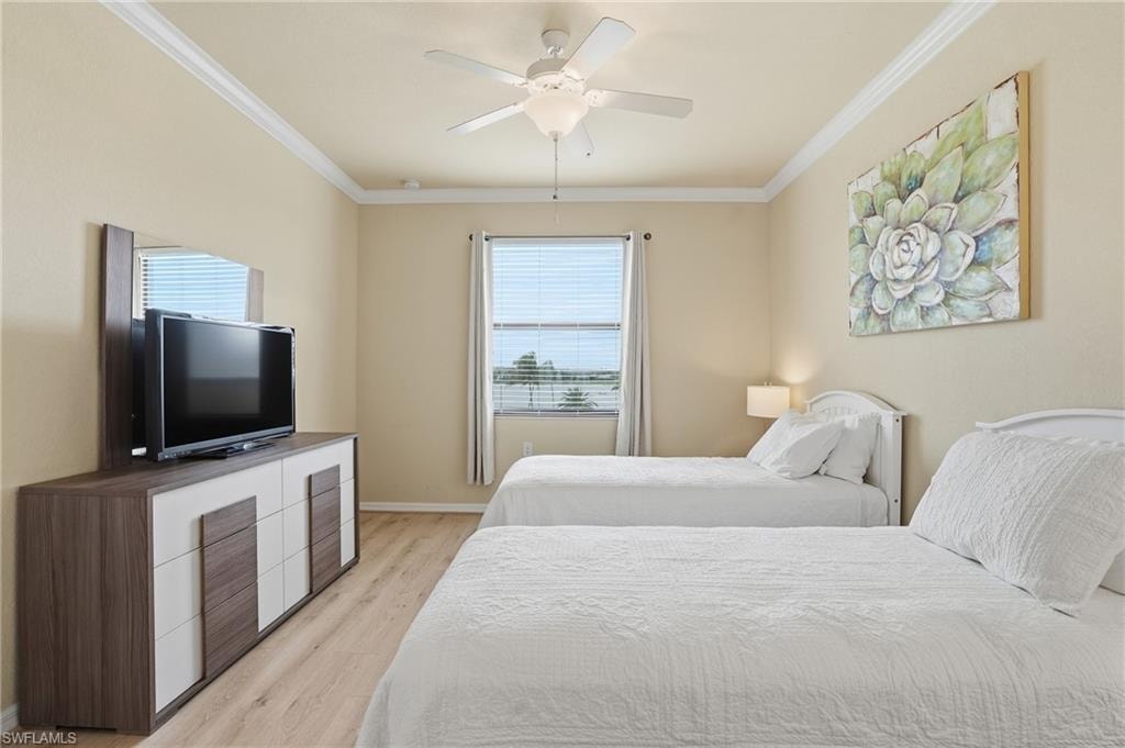 Bedroom with light wood finished floors, ornamental molding, and a ceiling fan