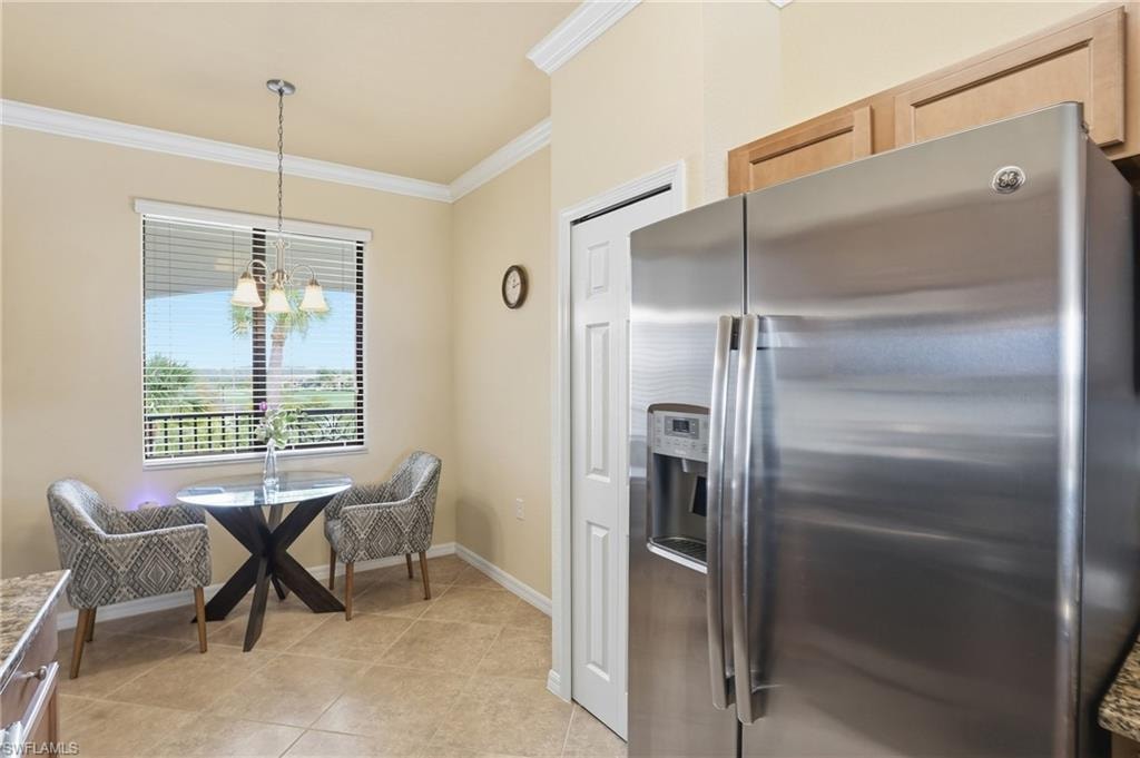 Kitchen with stainless steel fridge, ornamental molding, pendant lighting, a chandelier, and light tile patterned floors